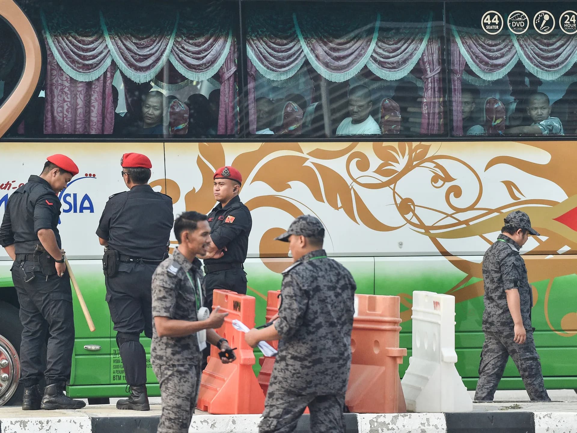 Agentes de seguridad malasios custodian un bus con ciudadanos de Myanmar que serán repatriados