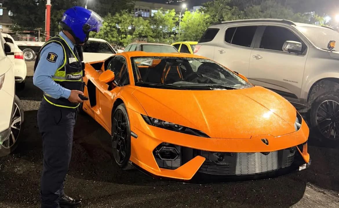 Un agente de tránsito revisa el Lamborghini naranja inmovilizado por la Secretaría de Movilidad de Medellín