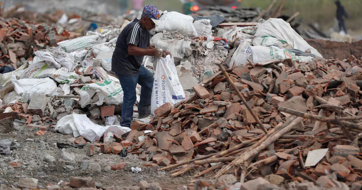 Un hombre recoge material entre los escombros acumulados tras el terremoto