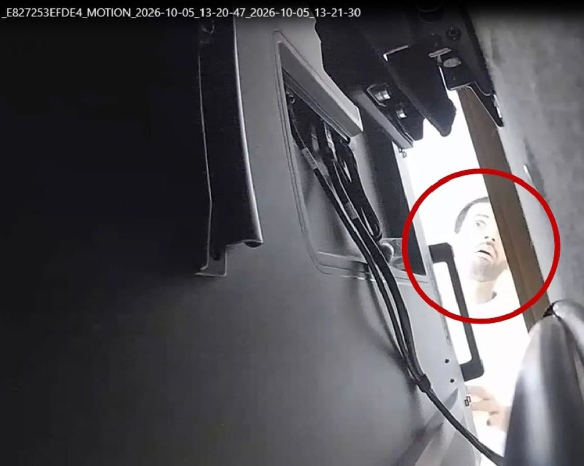 Imagen de una cámara de seguridad que muestra a un hombre mirando detrás de un televisor en una sala de reuniones
