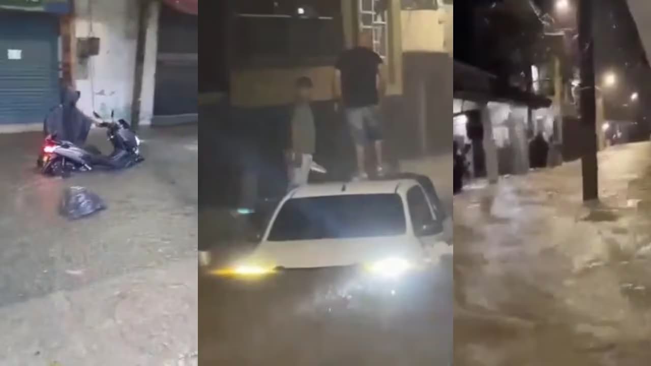 Calles de Quibdó anegadas de noche: una moto hundida hasta el motor frente a locales cerrados y una camioneta blanca avanzando con el agua por encima de las llantas