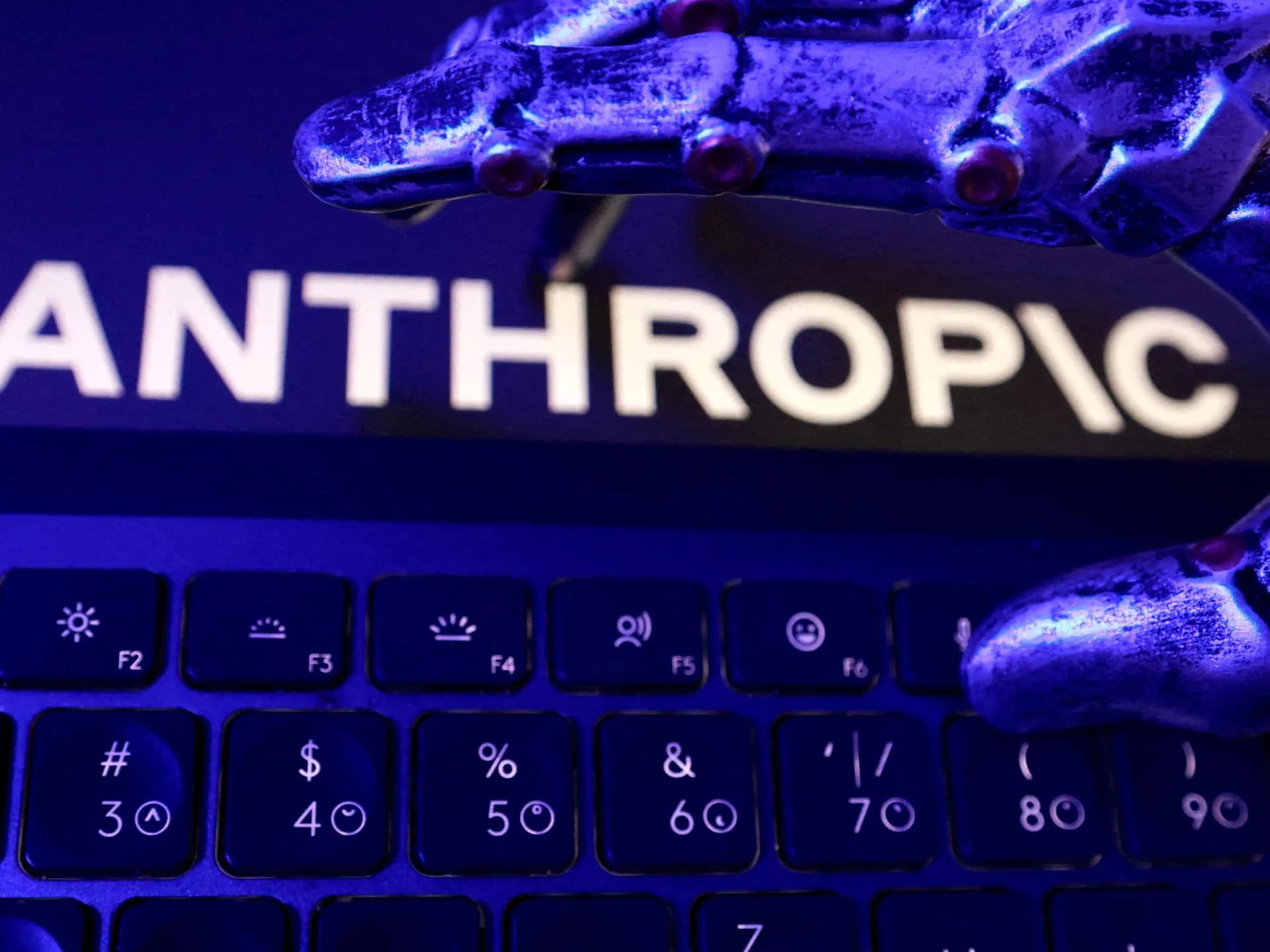 Una mano robótica sobre un teclado junto al nombre de la compañía en una pantalla