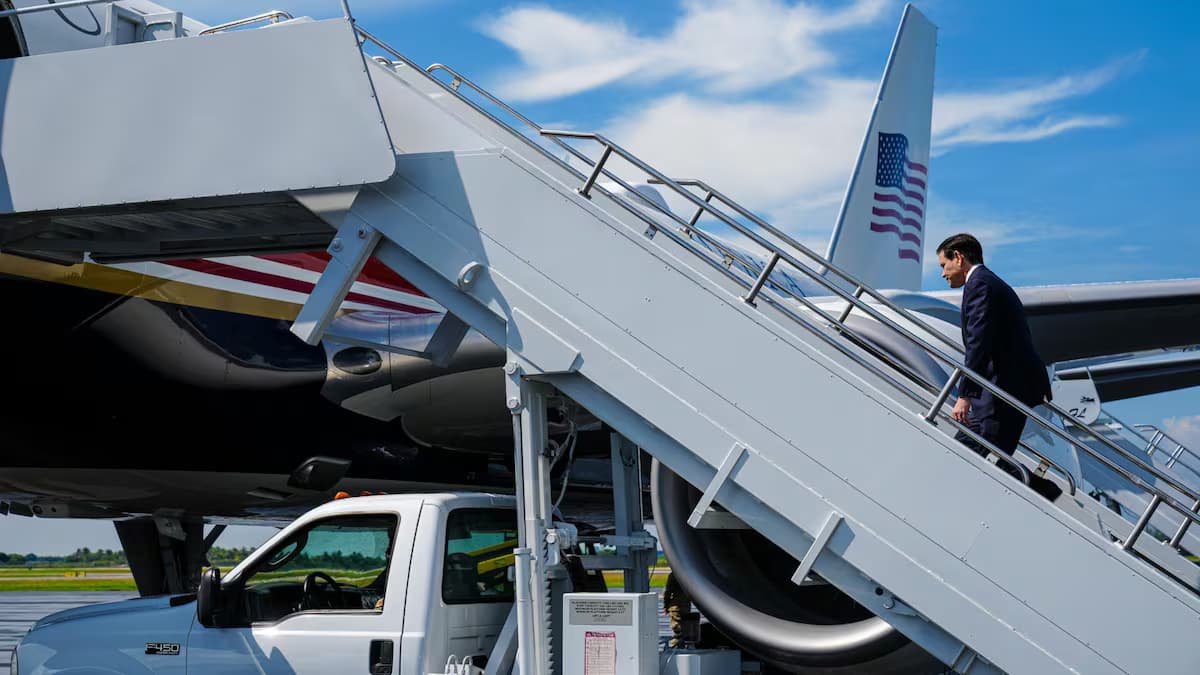 Un hombre de traje oscuro sube la escalerilla de un avión oficial de Estados Unidos