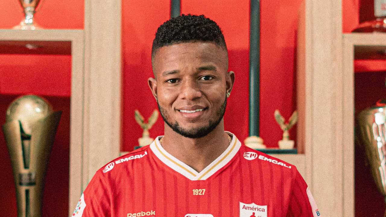 Yhormar Hurtado posa con la camiseta del América de Cali frente a una vitrina de trofeos