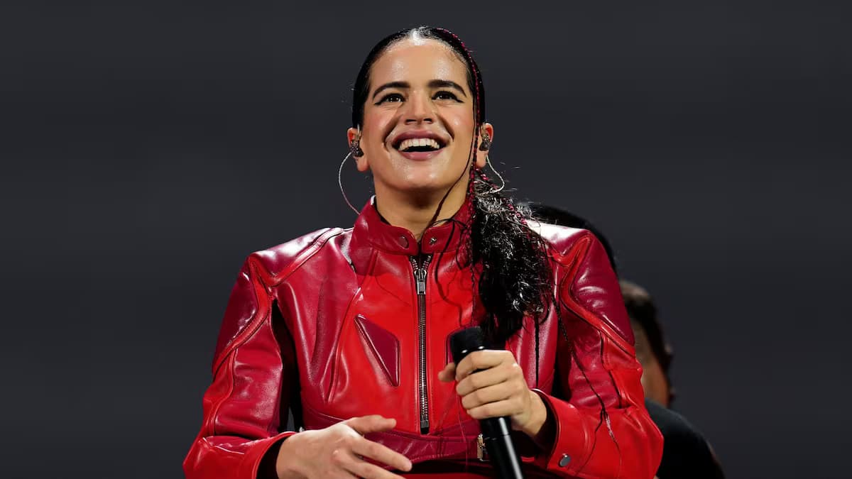 Rosalía sonríe con un micrófono en la mano durante un concierto