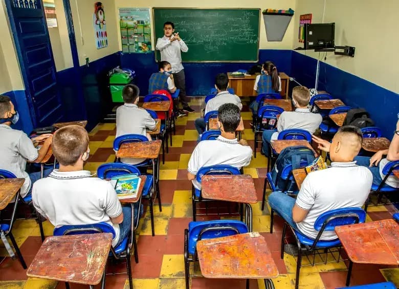 Estudiantes de bachillerato en un aula de un colegio público con su profesor frente al tablero