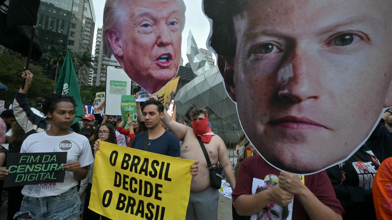 Manifestantes con pancartas contra la censura digital y caras gigantes de Mark Zuckerberg y Donald Trump frente a la sede de Meta en São Paulo