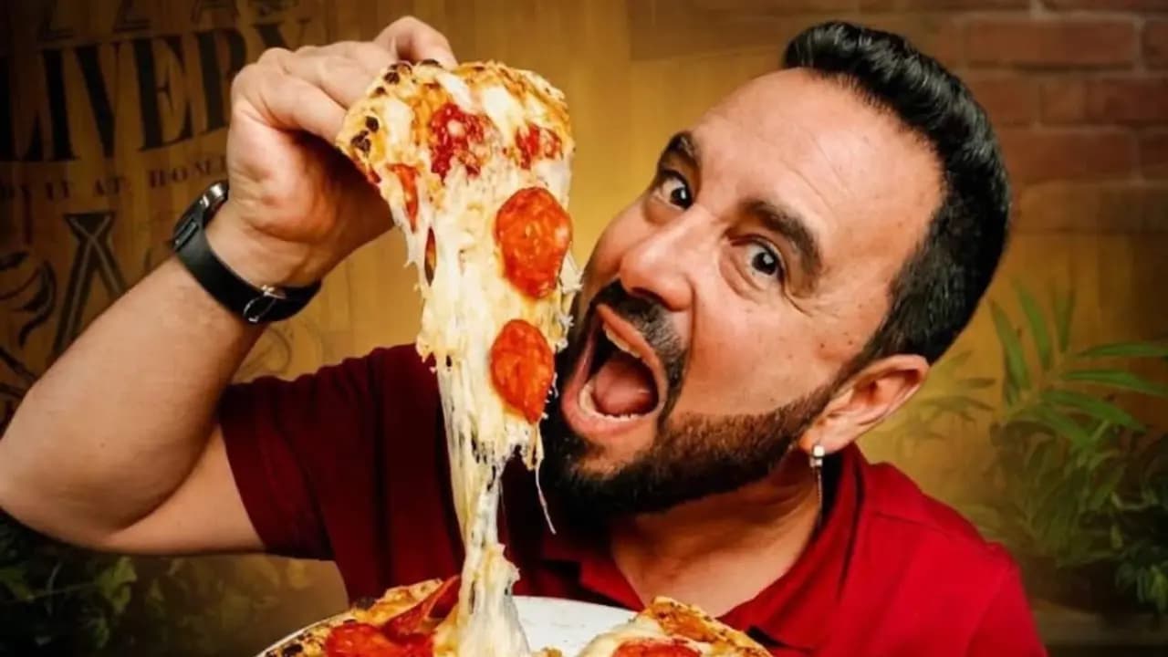 Tulio Zuloaga, creador de Tulio Recomienda, muerde una porción de pizza de pepperoni
