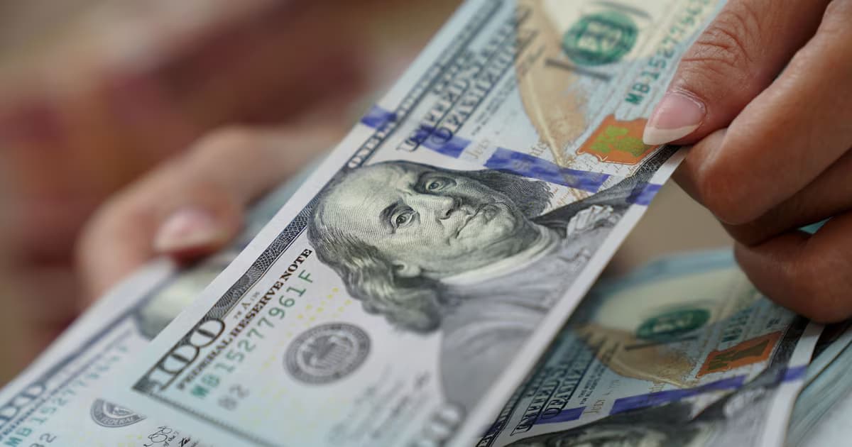 Una persona cuenta billetes de cien dólares en una casa de cambio