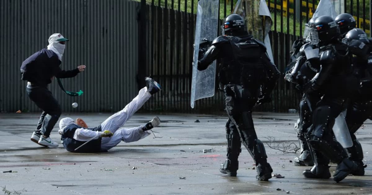 Agentes antidisturbios de la Policía con escudos frente a manifestantes encapuchados