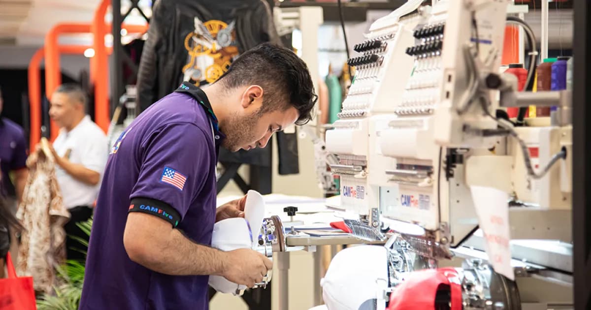 Un operario trabaja en una máquina bordadora industrial
