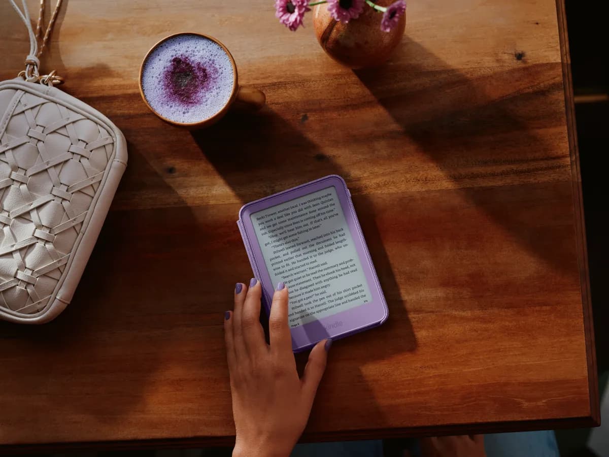 Una persona lee en un Kindle morado sobre la mesa de un café