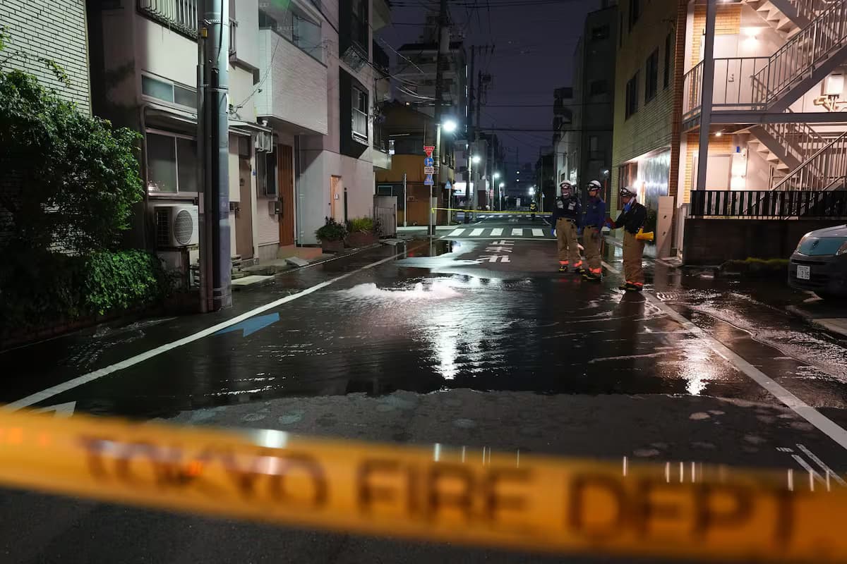 Bomberos trabajan de noche en una calle inundada por la rotura de una tubería tras el sismo en Japón