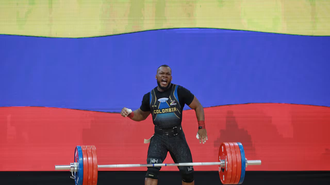 Yeison López celebra tras un levantamiento, con la bandera de Colombia de fondo