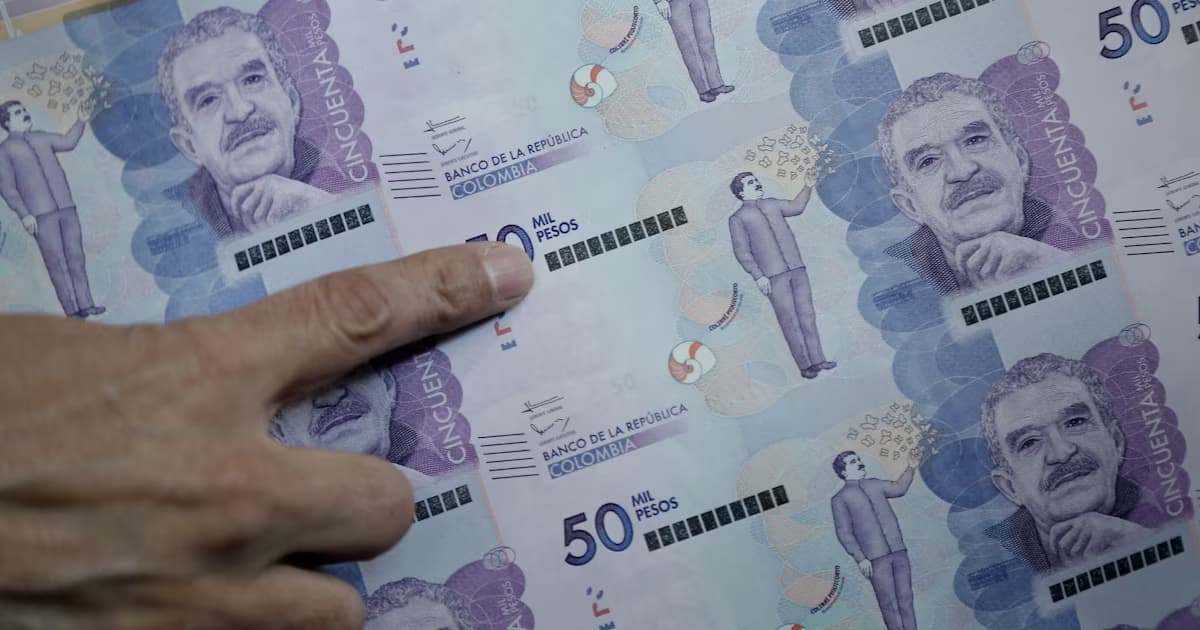 Una mano señala un pliego de billetes colombianos de 50.000 pesos