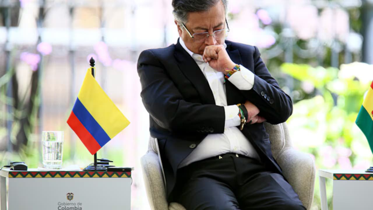 El expresidente Gustavo Petro, sentado y pensativo junto a una bandera de Colombia