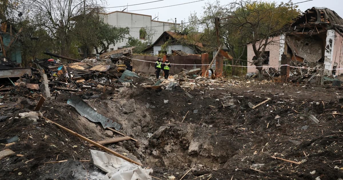 Policías ucranianos revisan un cráter y casas destruidas tras un ataque ruso en Kiev