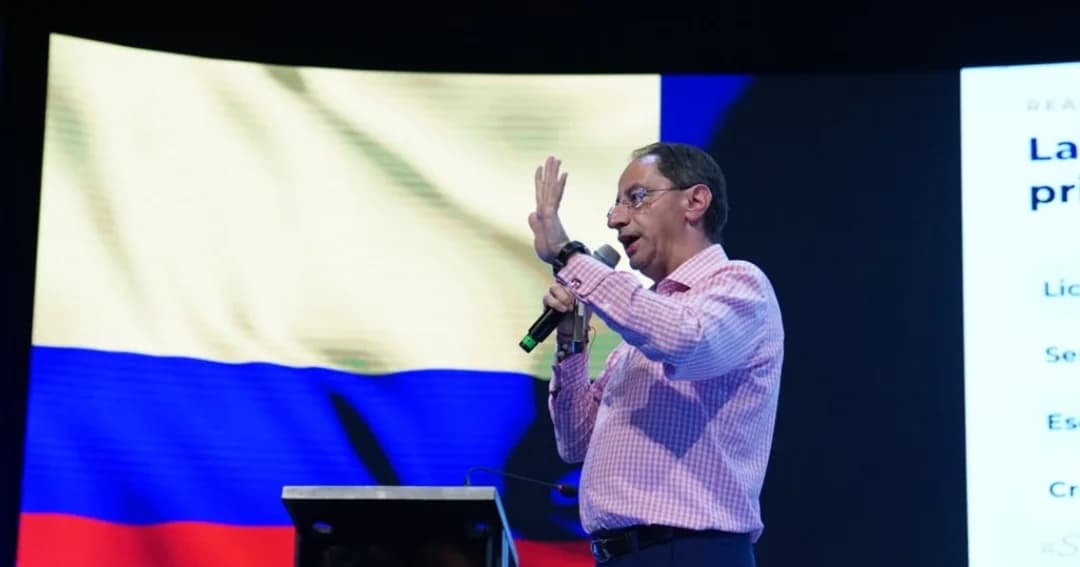 El vicepresidente José Manuel Restrepo habla con un micrófono en el escenario del Congreso Colombiano de la Construcción, frente a una pantalla con la bandera de Colombia