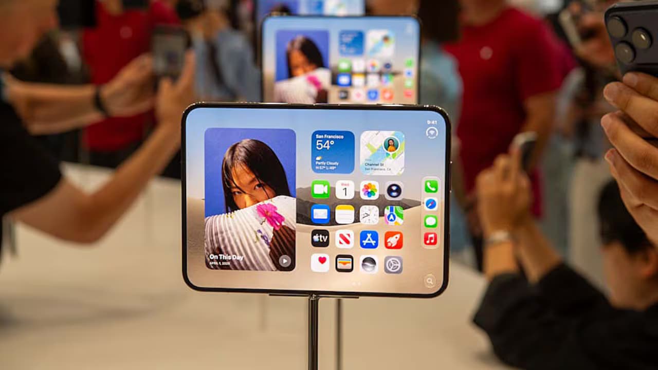 Un iPhone Duo desplegado en exhibición mientras asistentes toman fotos