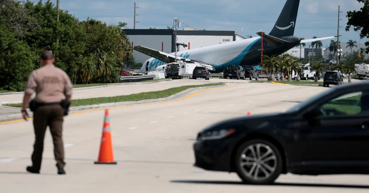 Un agente vigila una vía cerrada junto al avión de carga de Amazon accidentado en el aeropuerto de Miami