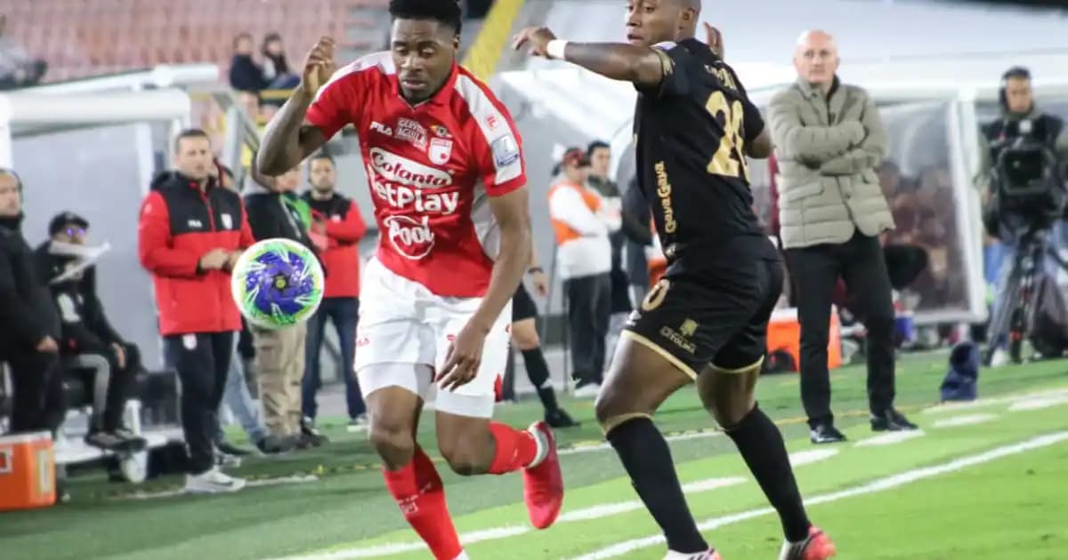 Un jugador de Santa Fe conduce el balón perseguido por un rival del Tolima en El Campín