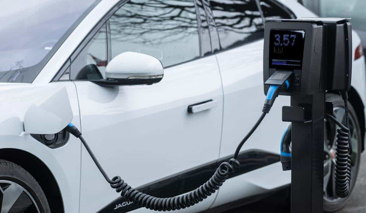 Un carro eléctrico blanco conectado a un cargador
