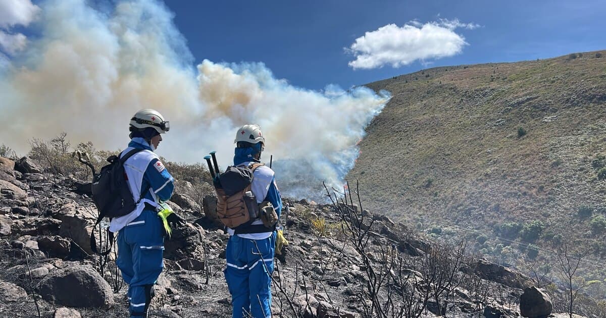 Dos socorristas de la Cruz Roja caminan sobre el páramo quemado entre el humo