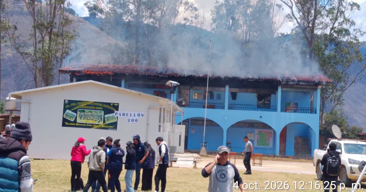 Humo sale del techo de un pabellón del colegio David Sánchez Infante, en Sorochuco, mientras personas observan desde el patio