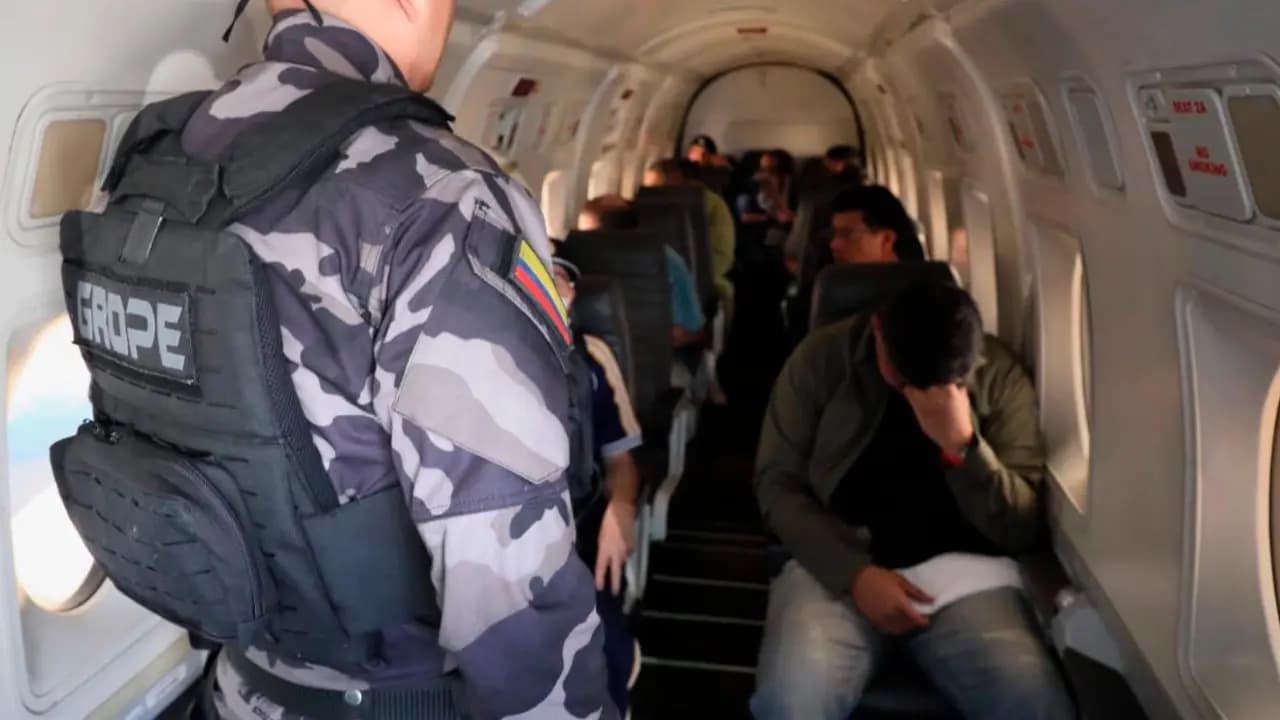 Agentes de un grupo especial custodian a varios internos sentados dentro de un avión durante un traslado carcelario