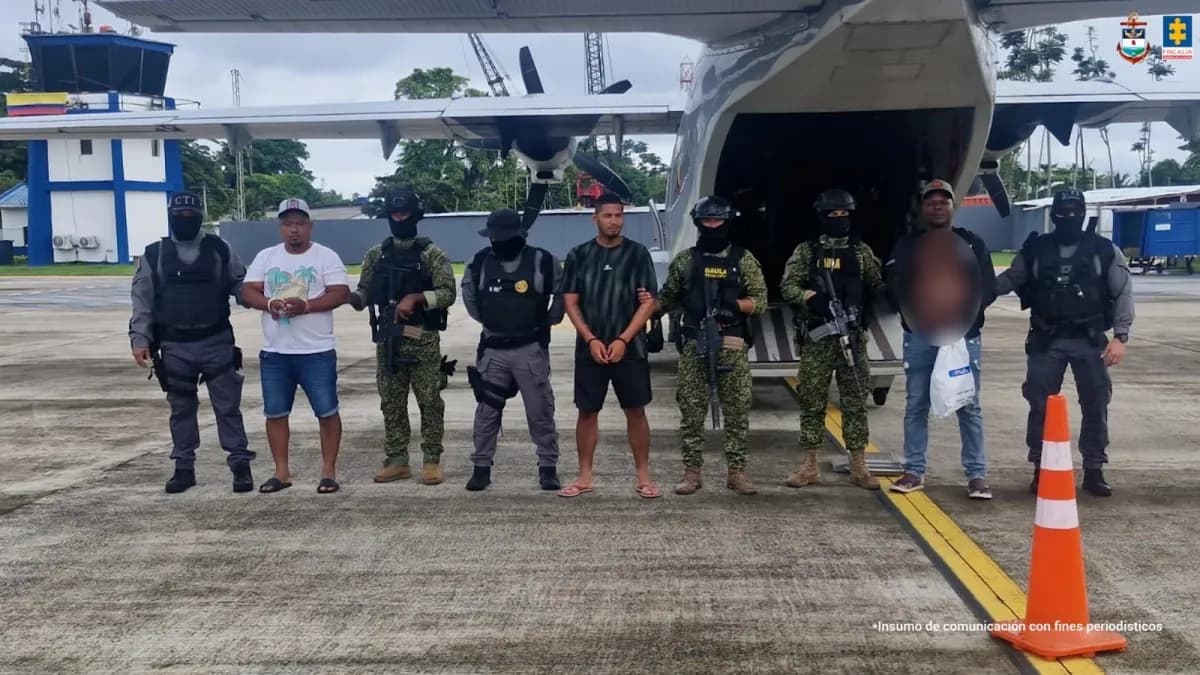 Cinco detenidos custodiados por uniformados del CTI y la Armada frente a un avión militar en una pista del Pacífico