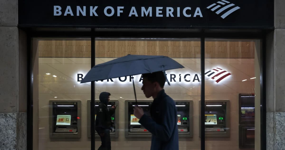 Un hombre con paraguas pasa frente a una sucursal de Bank of America