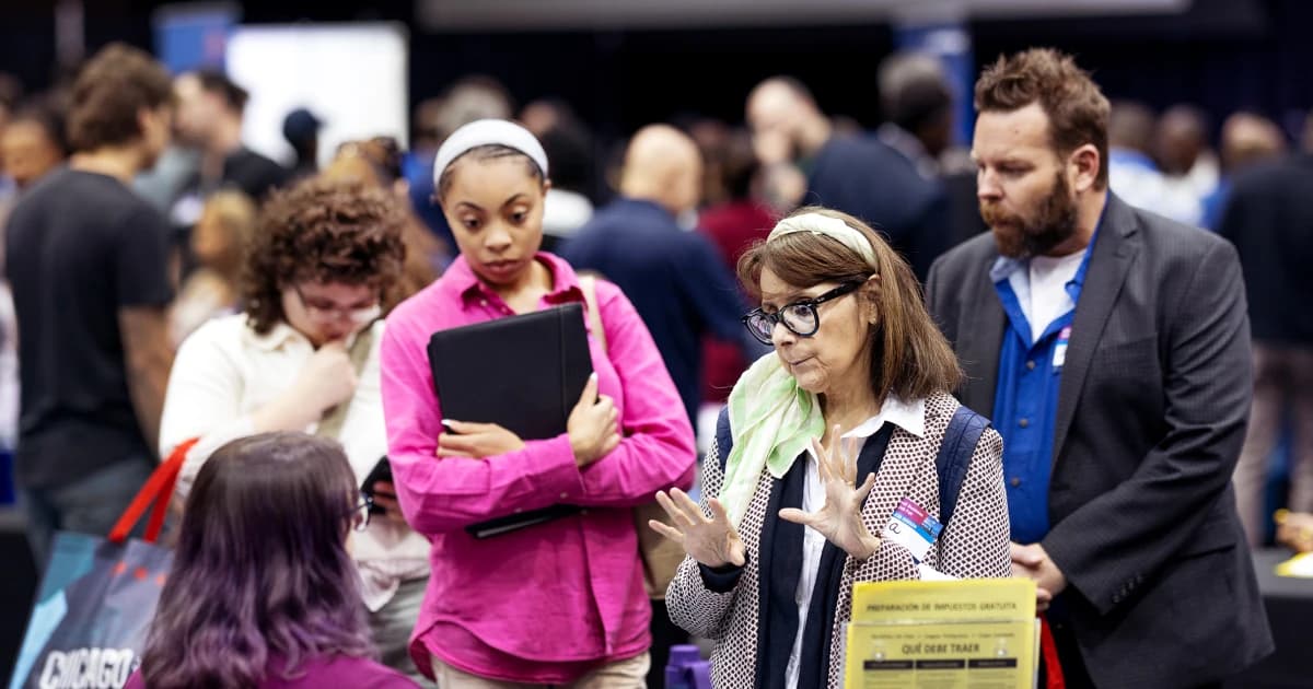 Personas en busca de trabajo conversan con reclutadores en una feria de empleo en Chicago