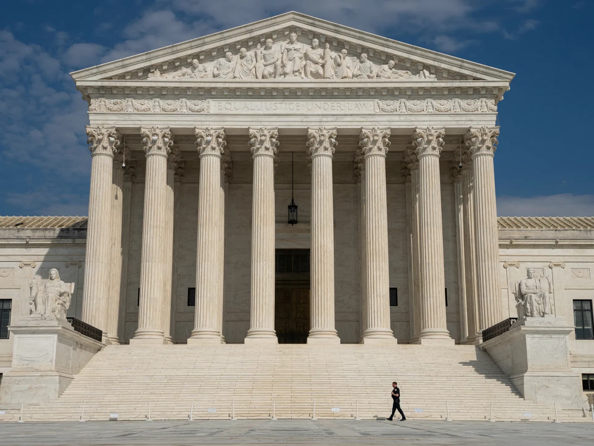 Fachada de la Corte Suprema de Estados Unidos en Washington con un agente caminando frente a la escalinata