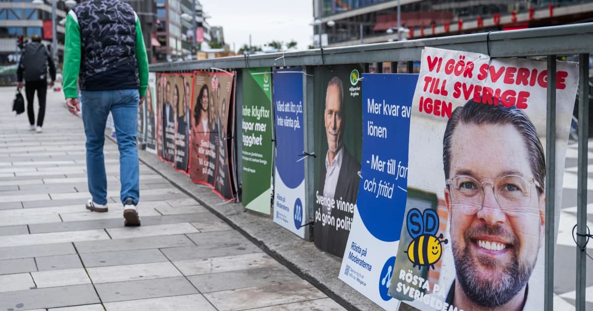 Un peatón pasa junto a carteles electorales de varios partidos colgados en una baranda de una calle de Estocolmo