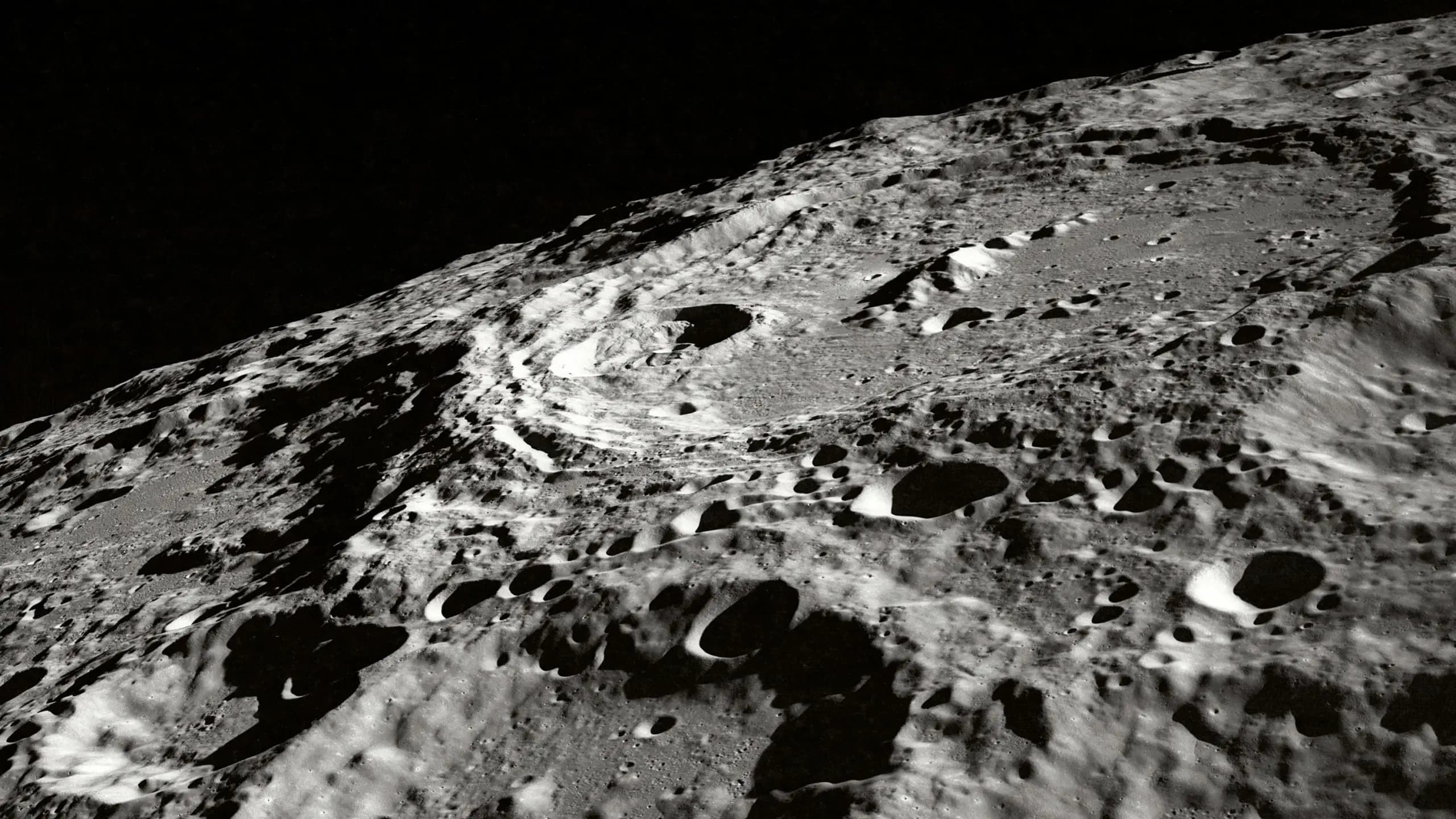 Vista oblicua en blanco y negro de la superficie de la Luna cubierta de cráteres