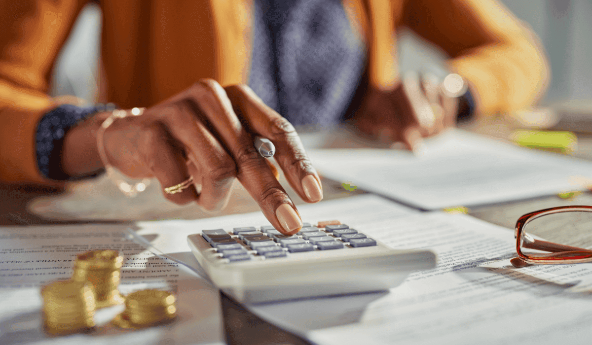 Una mujer hace cuentas con una calculadora sobre formularios de impuestos