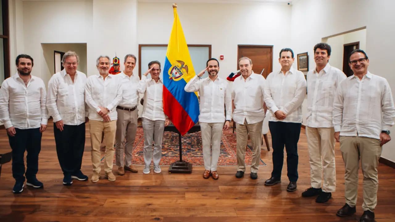 El presidente y un grupo de banqueros posan de pie junto a la bandera de Colombia tras la reunión sobre los alivios financieros