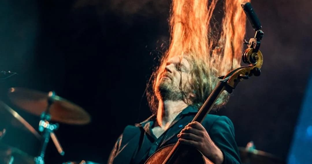 Un violonchelista agita su cabellera durante un concierto de rock