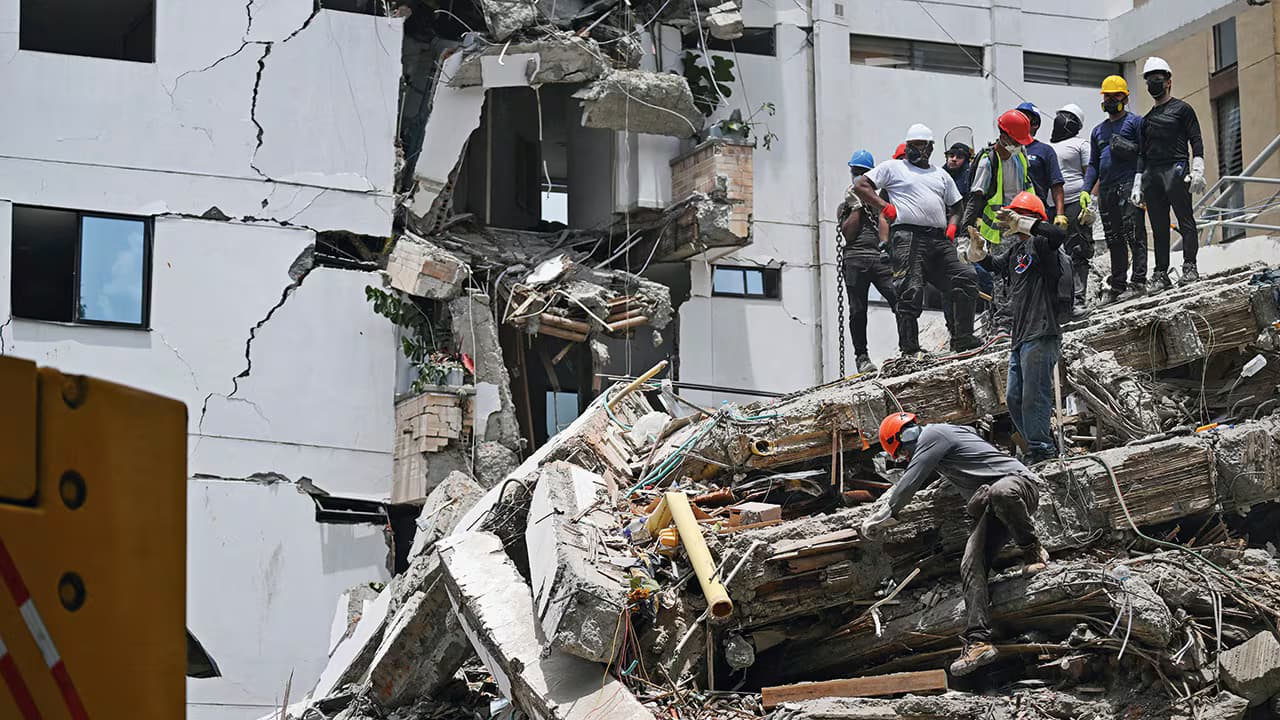 Rescatistas trabajan sobre los escombros de un edificio de apartamentos partido por el sismo