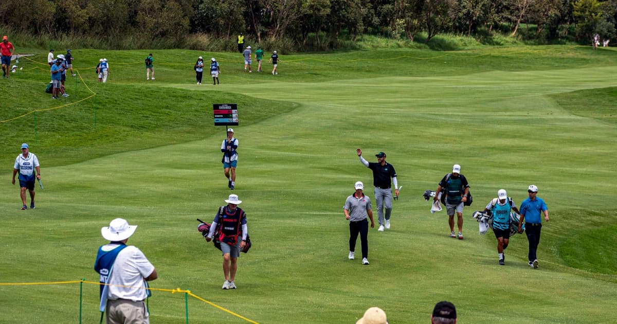 Golfistas y caddies recorren la calle de un campo durante un torneo