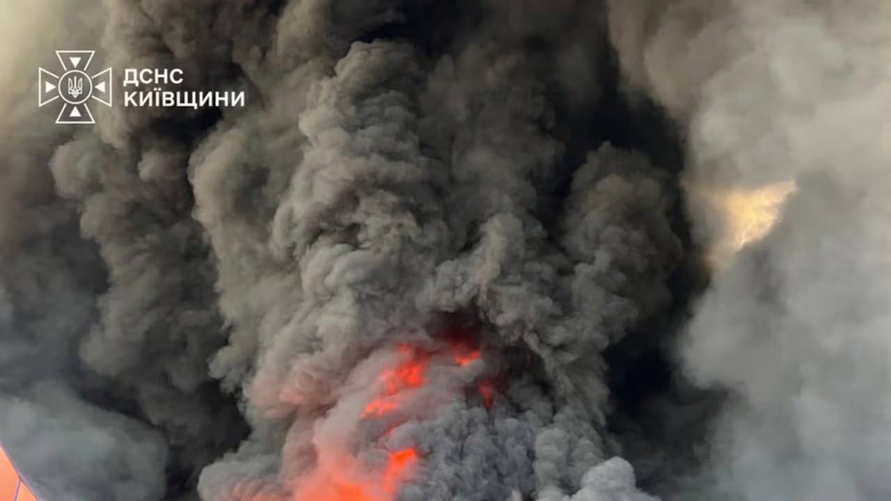 Enorme columna de humo negro con llamas anaranjadas en su base sobre la zona del depósito alcanzado