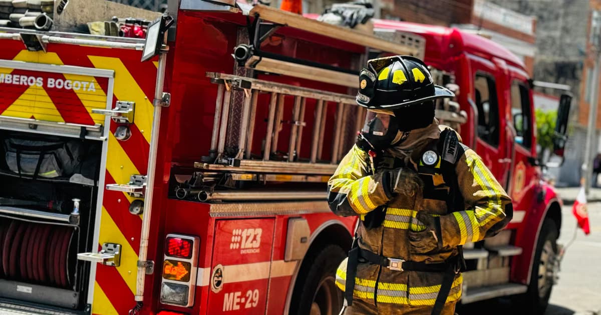 Un bombero con traje de protección frente a una máquina de Bomberos Bogotá