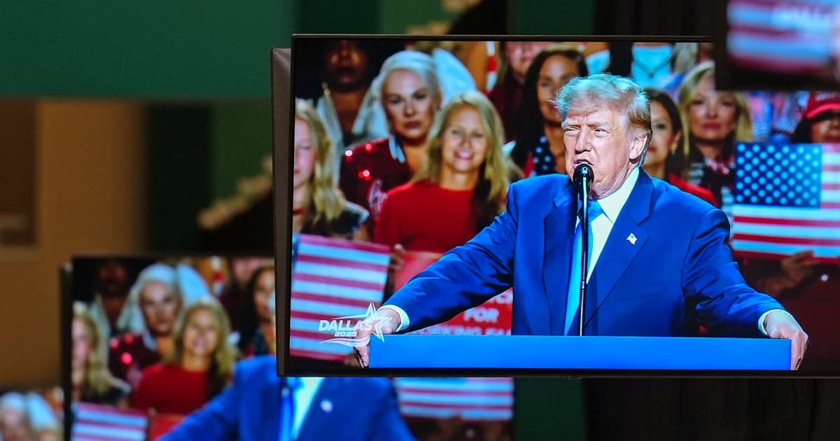 Pantallas de televisión muestran a Donald Trump hablando en un atril durante un acto con público