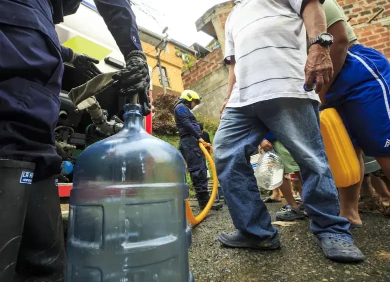 Habitantes de Medellín llenan recipientes con agua durante los cortes del servicio