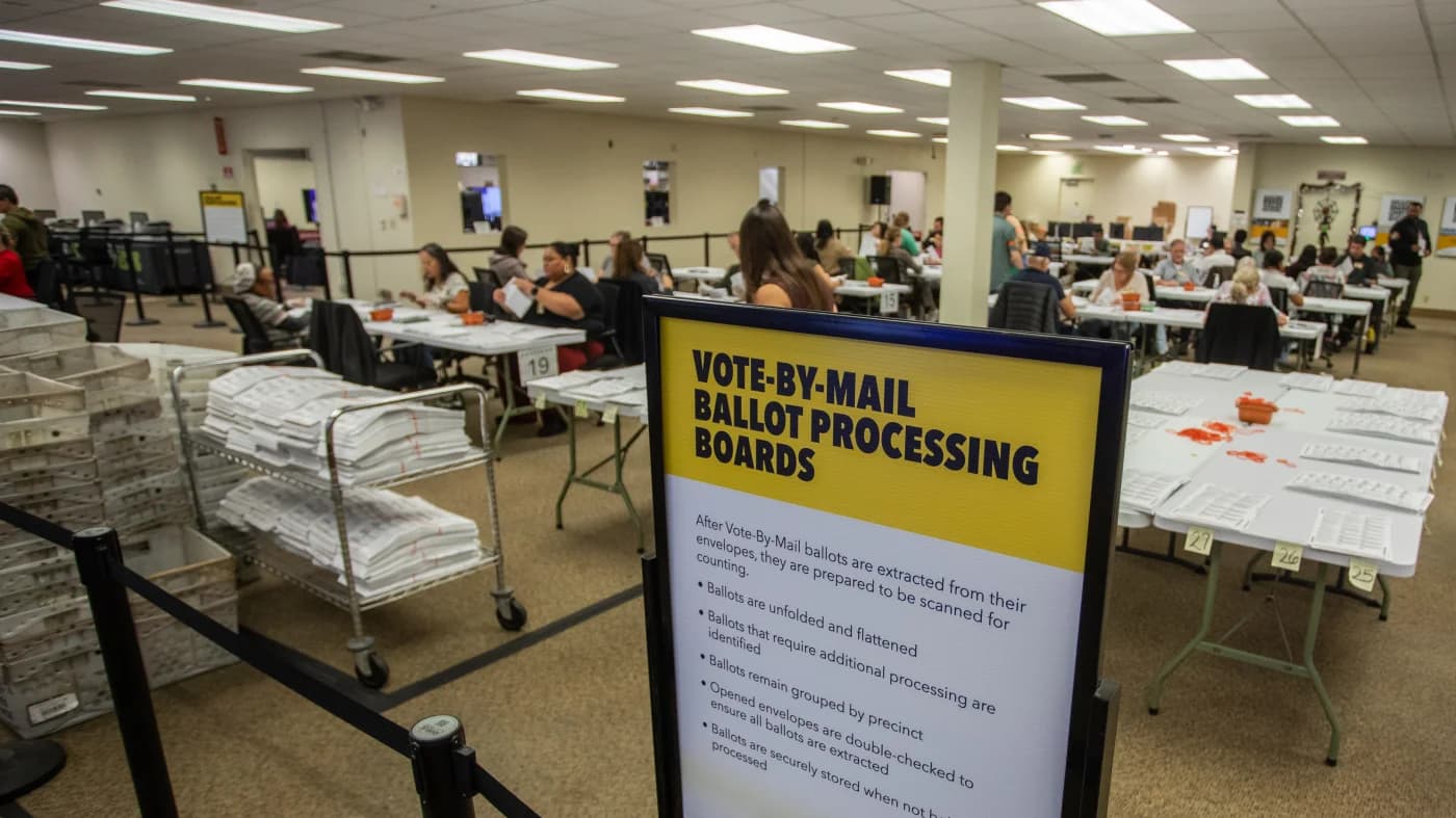 Trabajadores electorales sacan votos de sus sobres para escanearlos en el condado de Orange, California