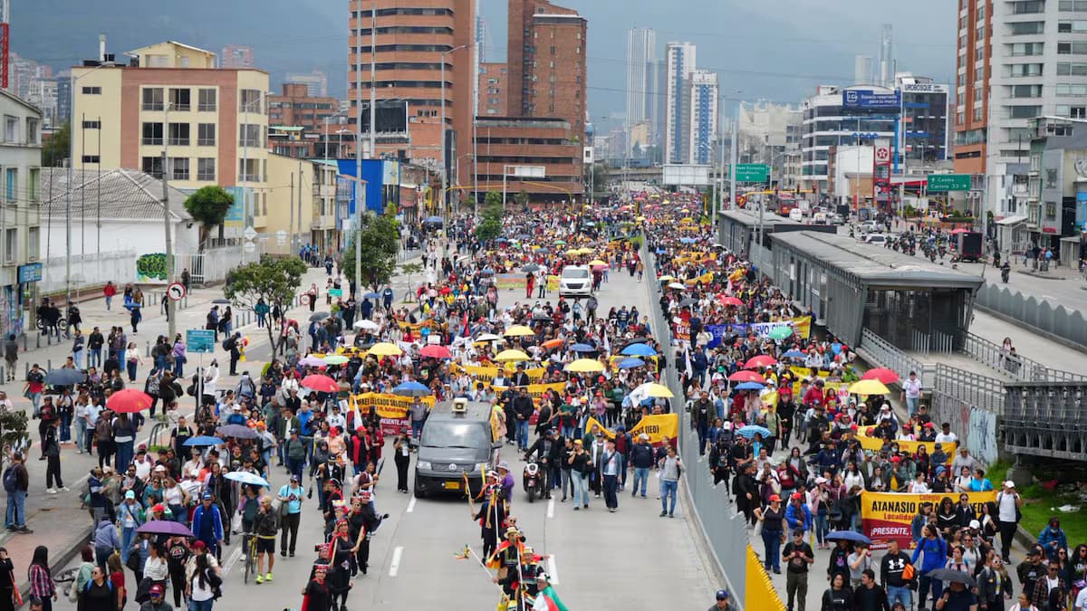 Miles de manifestantes marchan por una avenida de Bogotá junto a una estación de TransMilenio
