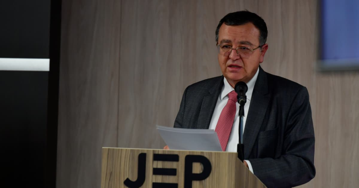 Alejandro Ramelli habla desde un atril con el logotipo de la Jurisdicción Especial para la Paz