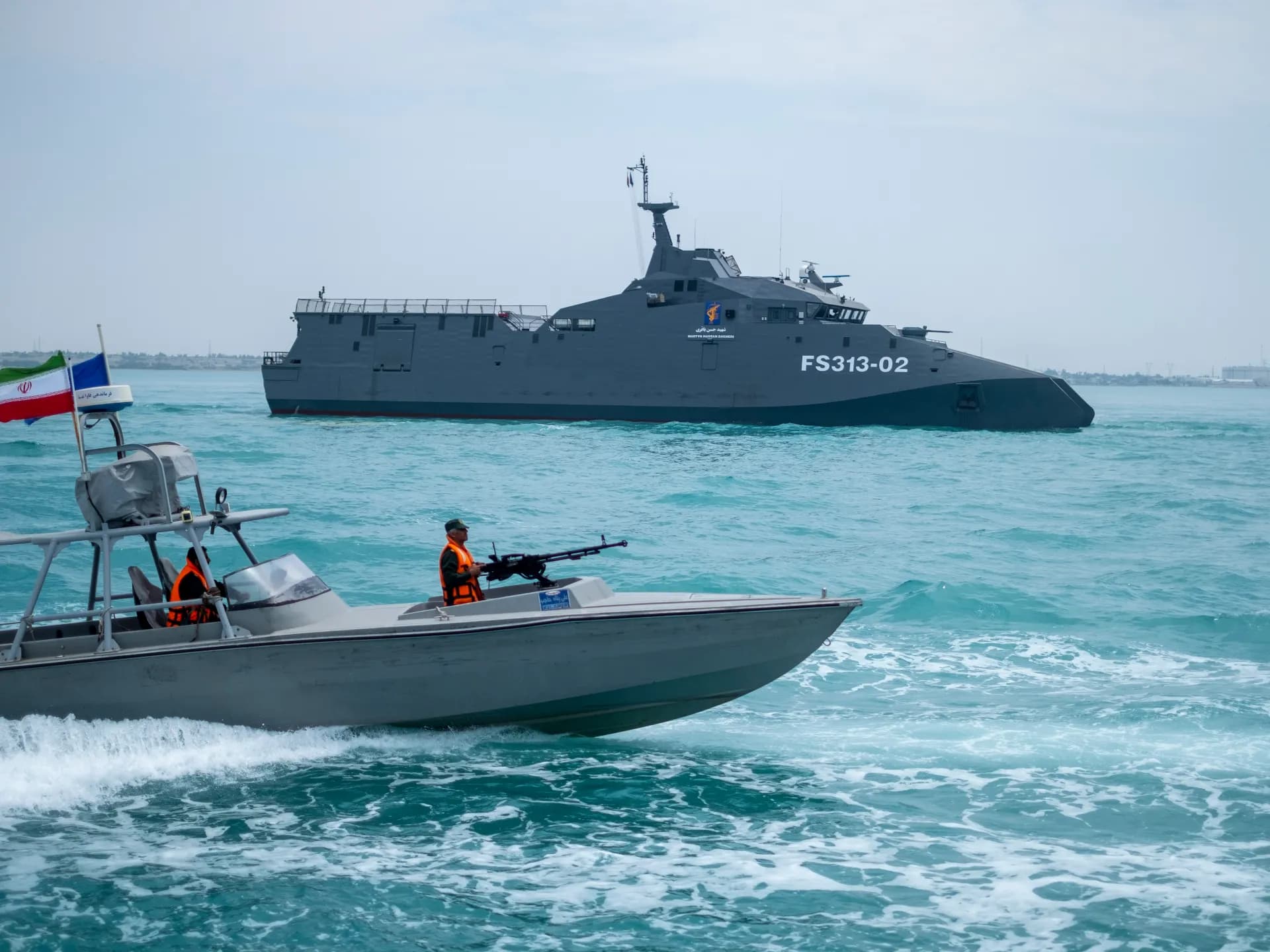 Lancha armada de la Guardia Revolucionaria iraní frente a un buque de guerra en el golfo Pérsico