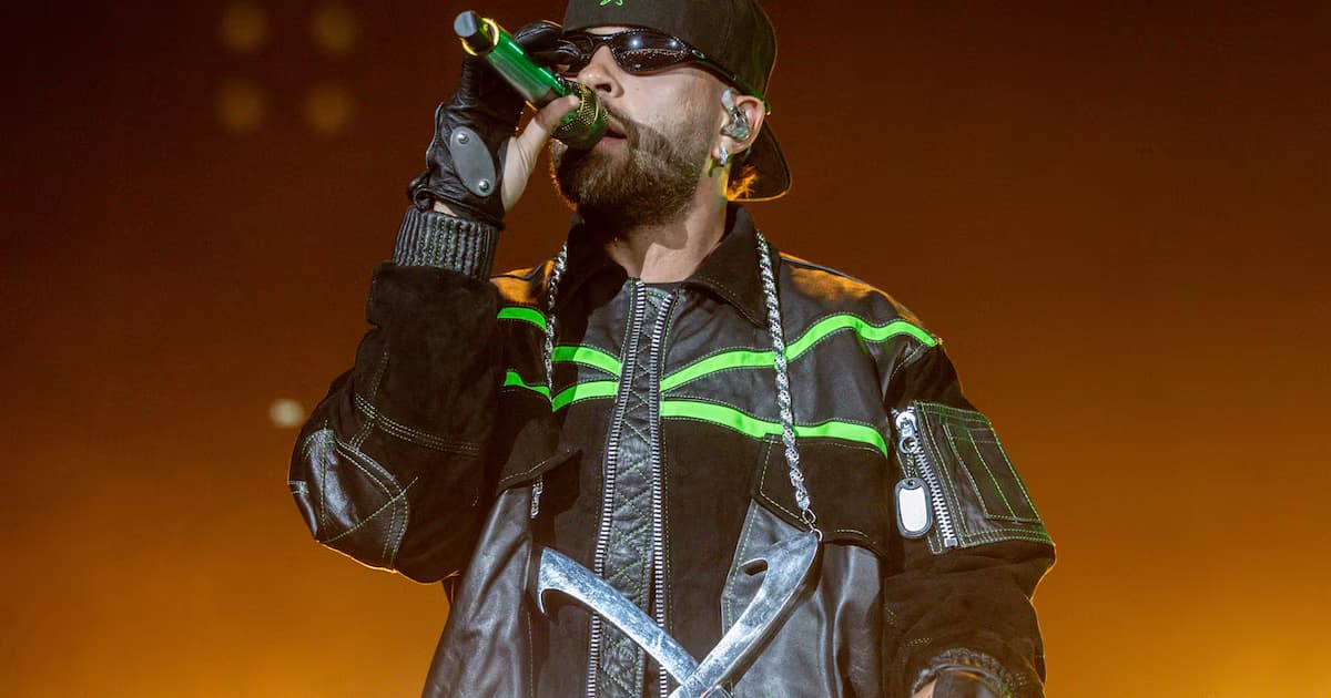 Feid canta en un concierto con gafas oscuras y chaqueta negra con franjas verdes