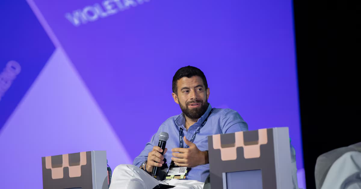 Una tarjeta de Revolut sostenida en la mano frente a un teléfono móvil